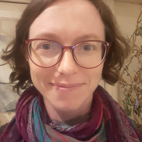 a head and shoulders shot of cath heinemeyer, a young white woman wearing glasses and a colourful scarf