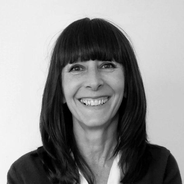 a black and white head and shoulders photo of Jane Wells, a white woman with long dark hair wearing a dark coloured jacket