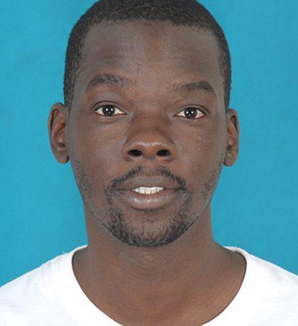 a head and shoulders photograph of John Mukeni Namai, a young black man with short hair and beard wearing a white t shirt