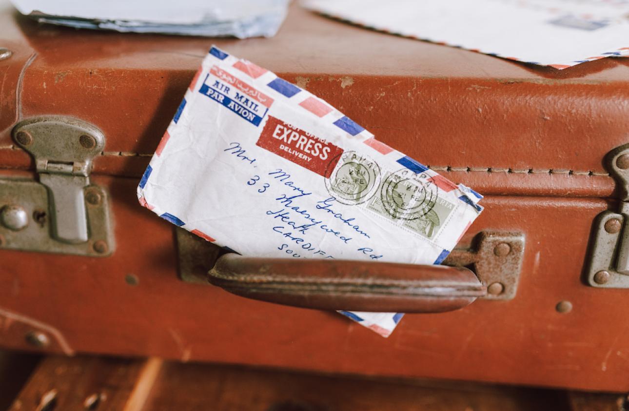 an old brown suitcase with an air mail envelope positioned in the handle